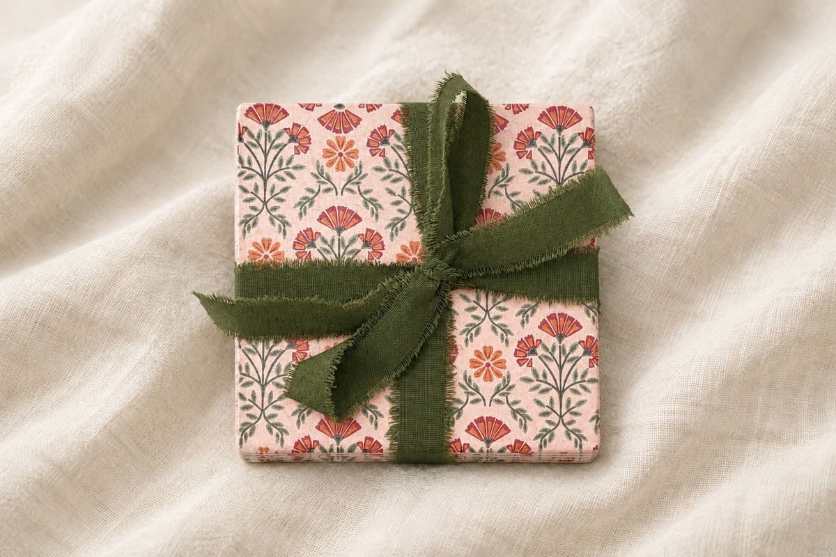 Dusty rose ribbon-tied set of four coasters on soft ivory linen